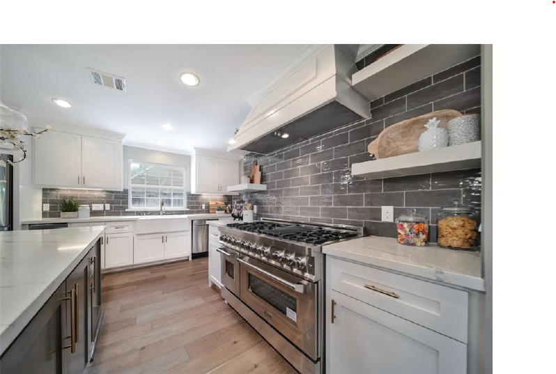 Bright modern kitchen with stainless steel stove, white cabinets, gray tile backsplash, and wood floors