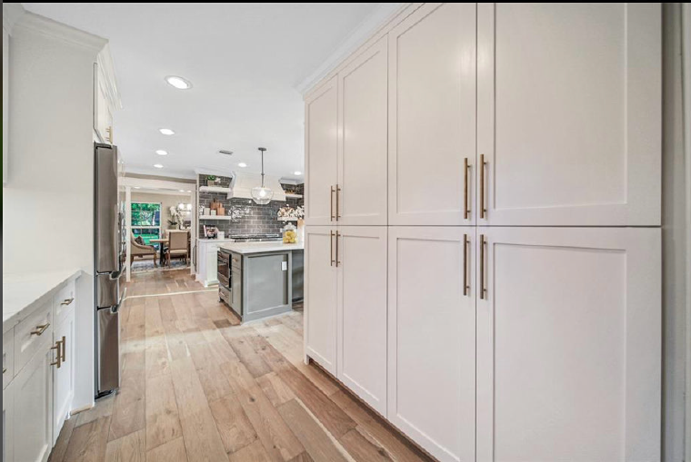 Bright modern kitchen with white cabinets, wood floors, and a view into the dining area