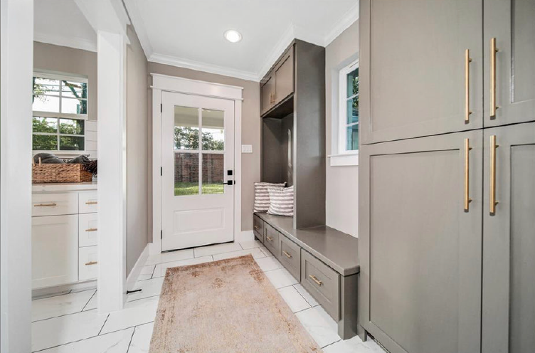 Bright modern mudroom with gray built-in storage, white bench, and a door with windows