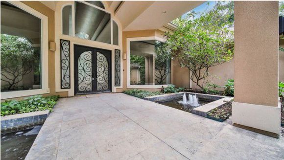 Front entrance of a modern home with a covered patio, double doors, and landscaped walkway with planters Front entrance of a modern home with a covered patio, double doors, and landscaped walkway with planters