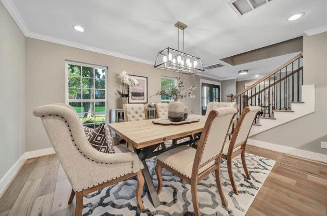 Modern dining room with a wood table, upholstered chairs, chandelier, and staircase Modern dining room with a wood table, upholstered chairs, chandelier, and staircase