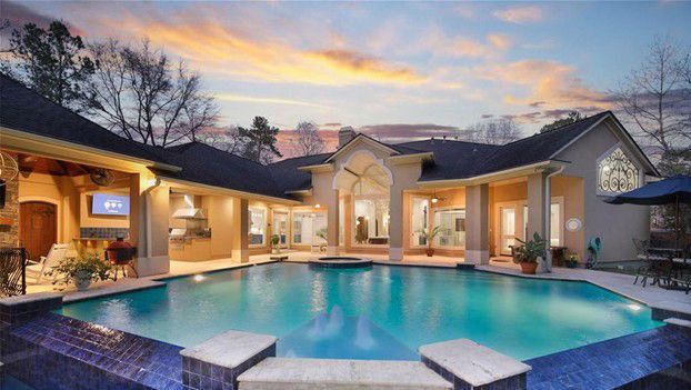 Luxury backyard pool with turquoise water, stone patio, and warm lights at sunset Luxury backyard pool with turquoise water, stone patio, and warm lights at sunset