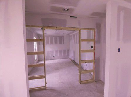Unfinished room with drywall and yellow scaffold frame in a doorway, carpeted floor, and ceiling light opening