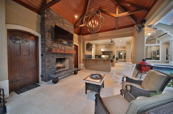 Cozy living room with stone fireplace, wood-beamed ceiling, and open view to kitchen and dining area