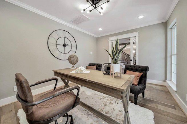 Modern dining room with a light wood table, mixed chairs, wall art, and large windows