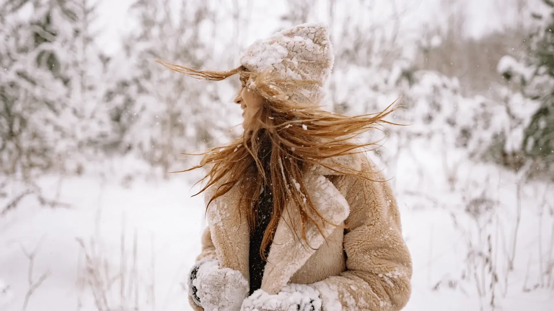 A woman in a fur coat and hat is standing in the snow.