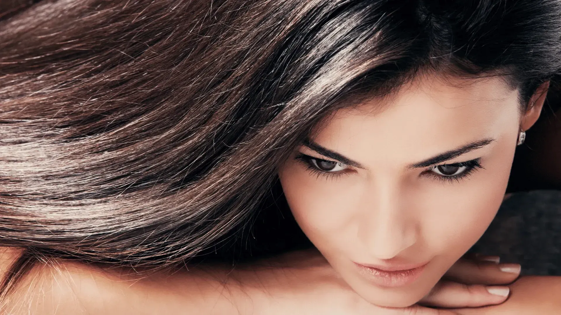 A close up of a woman 's face with her hair blowing in the wind.