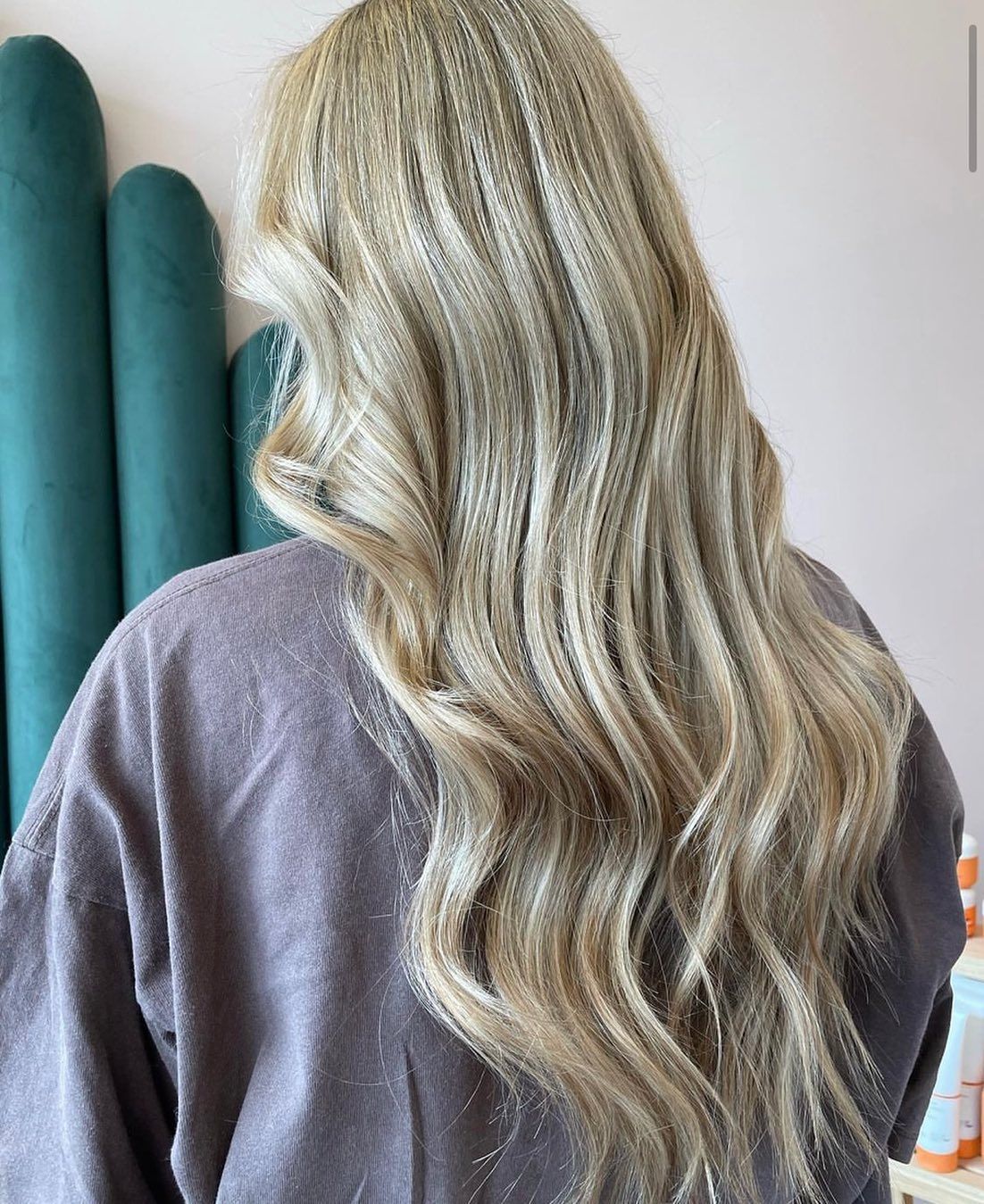 a woman with long blonde hair is wearing a grey sweater .