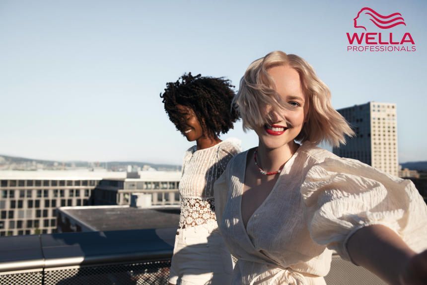 two women are posing for a wella professional photo