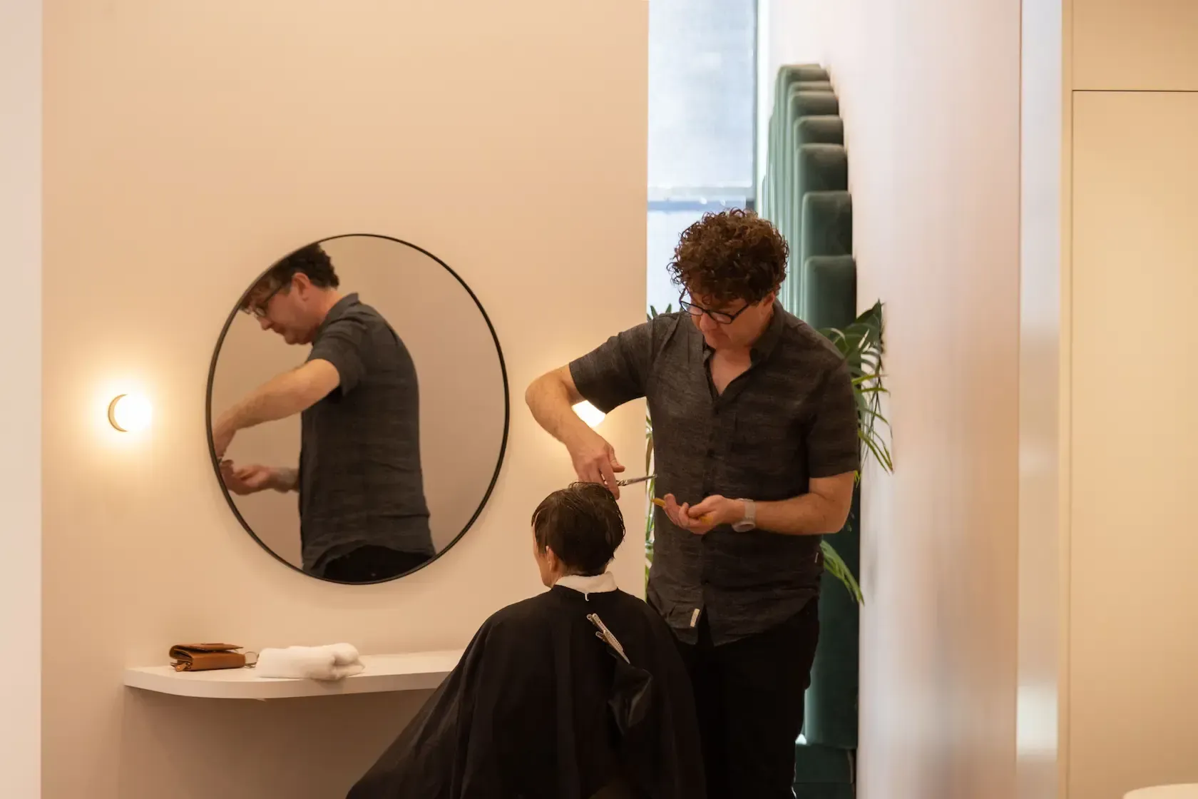 A man is cutting a boy 's hair in a salon.