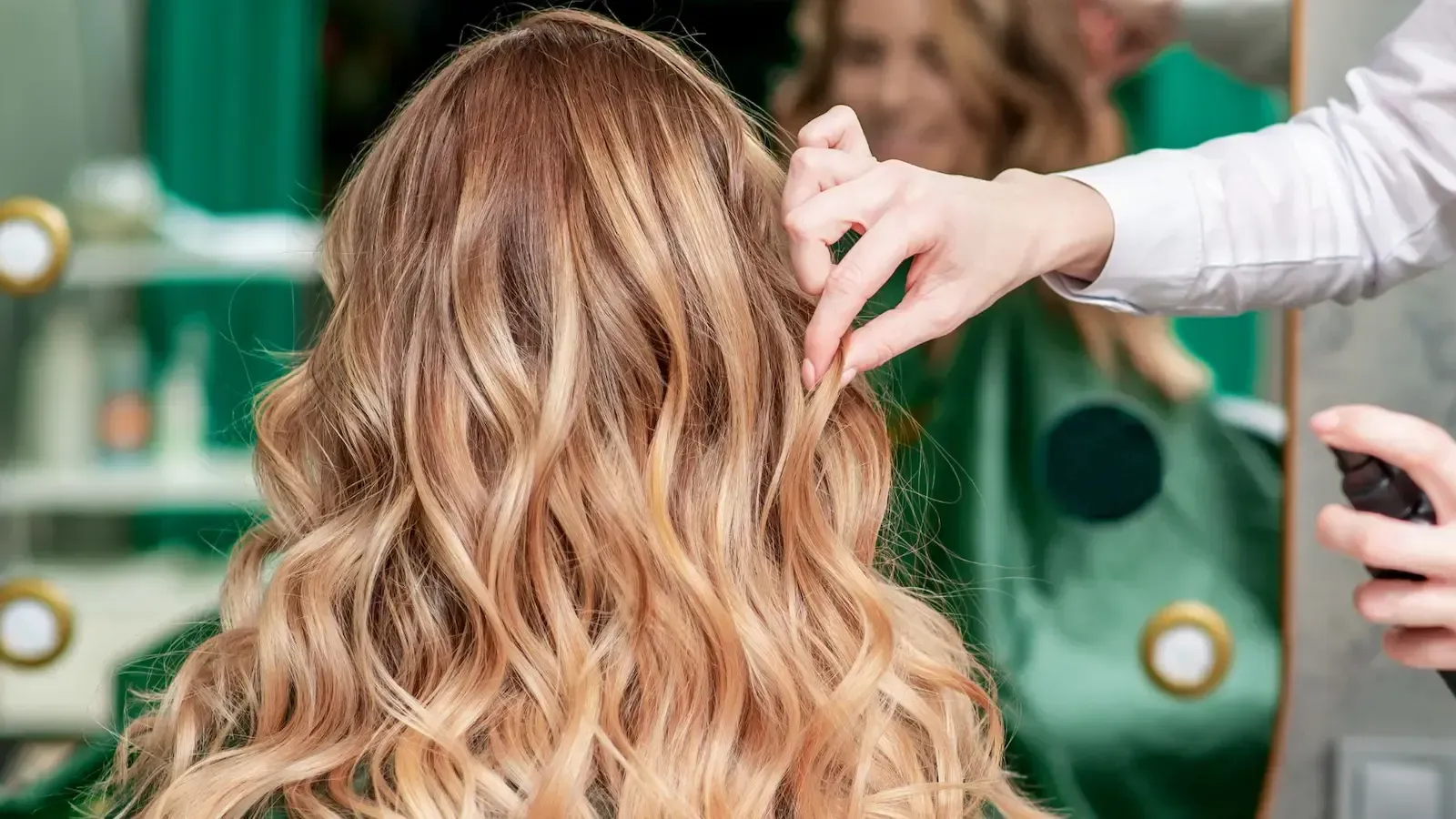 A woman is getting her hair done by a hairdresser in a salon.