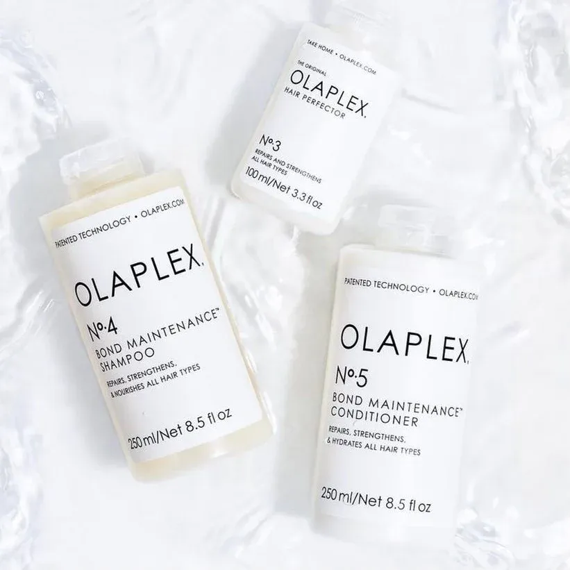 three bottles of olaplex hair products are sitting on a table .