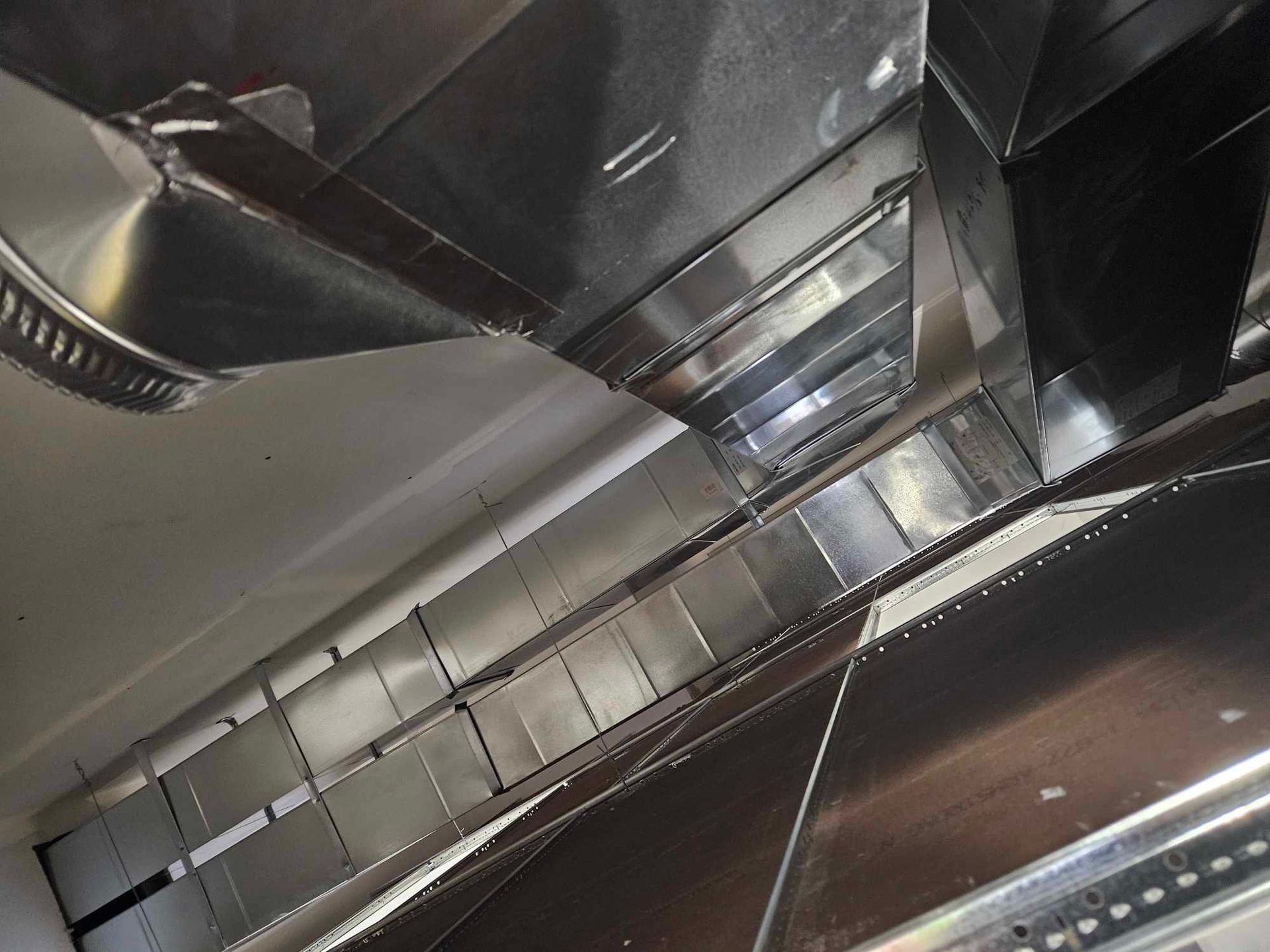 Une cuisine avec des appareils en acier inoxydable et un ventilateur de plafond.