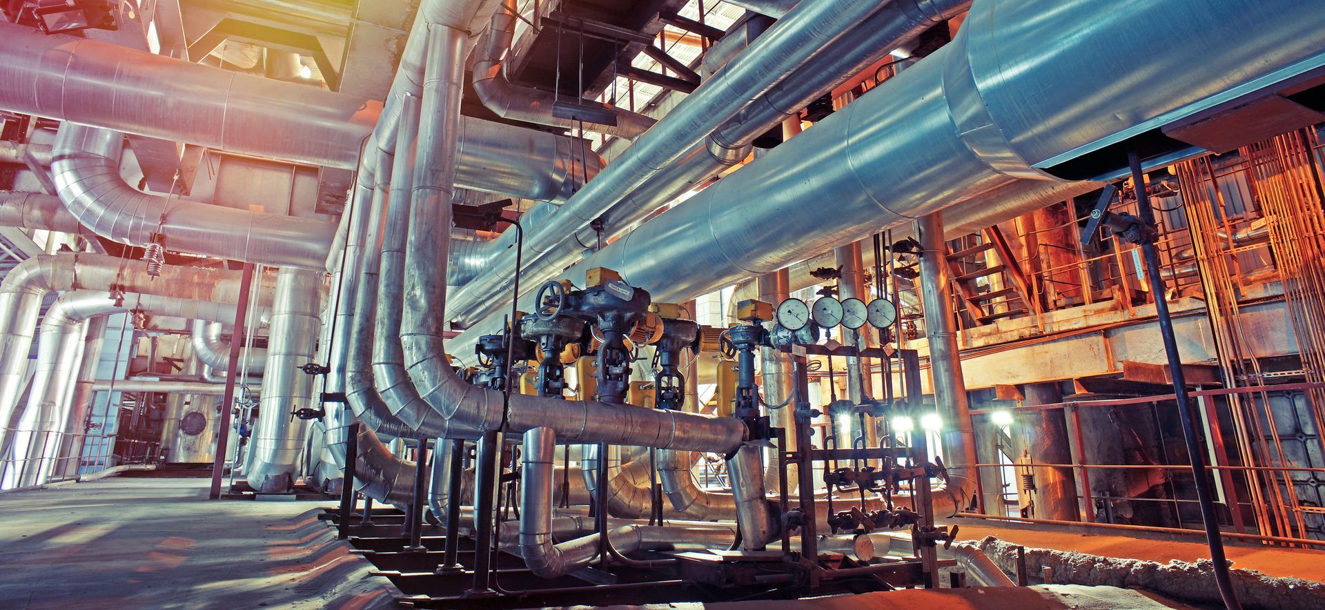 Cadre industriel avec de nombreuses canalisations et machines.
