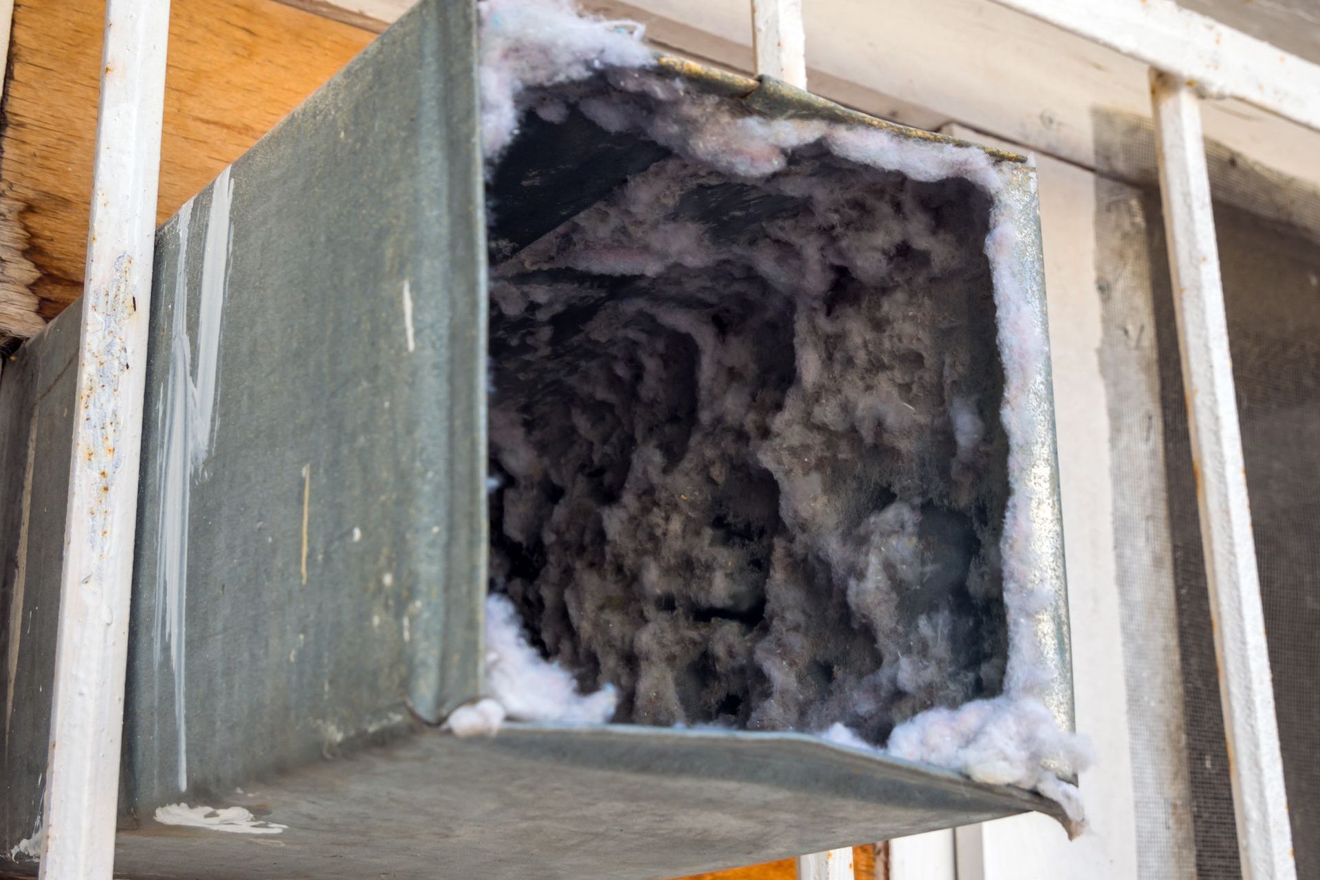 A dirty air duct with a lot of dust coming out of it.