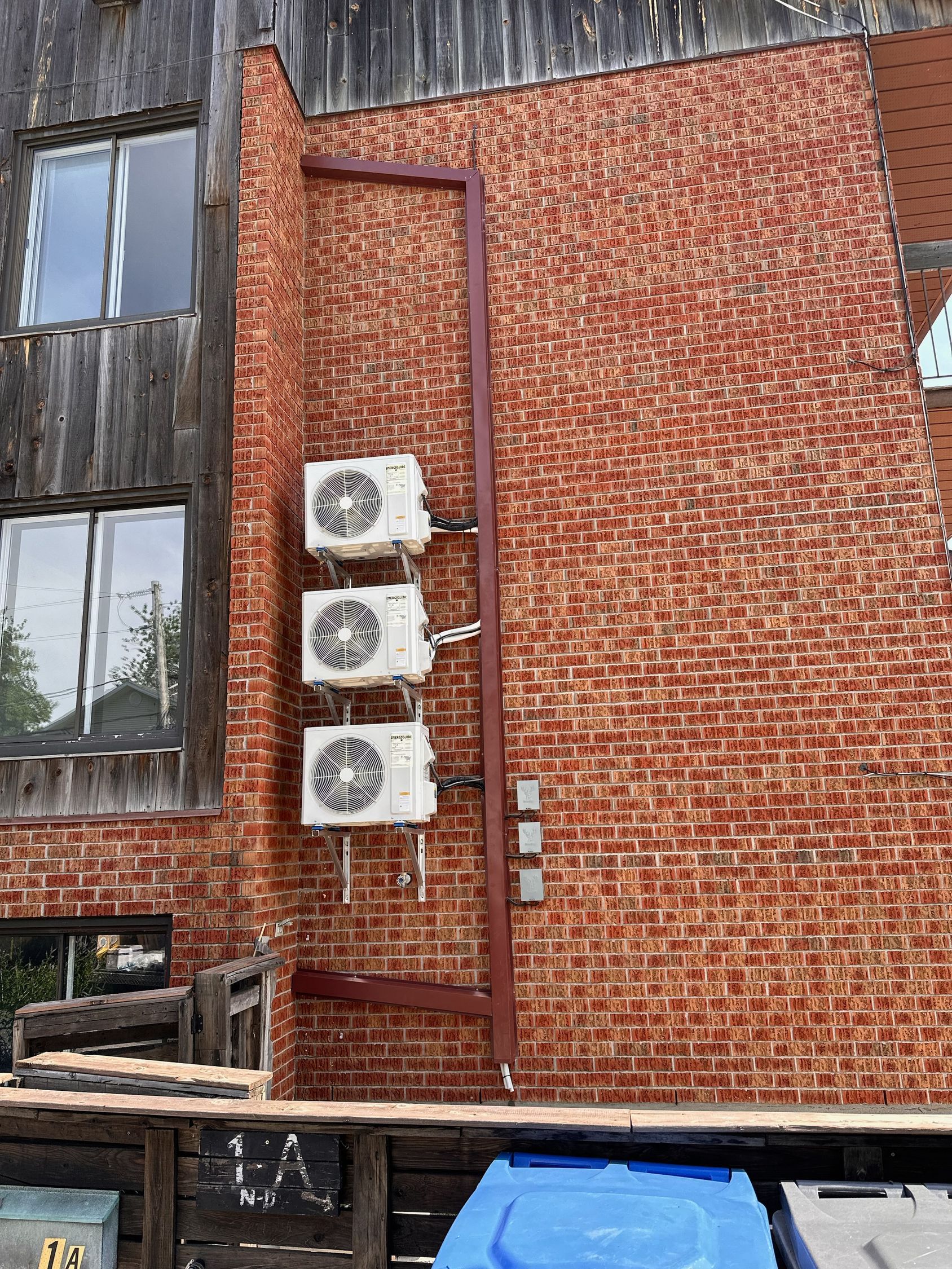 Trois climatiseurs sont montés sur le côté d'un bâtiment en briques.