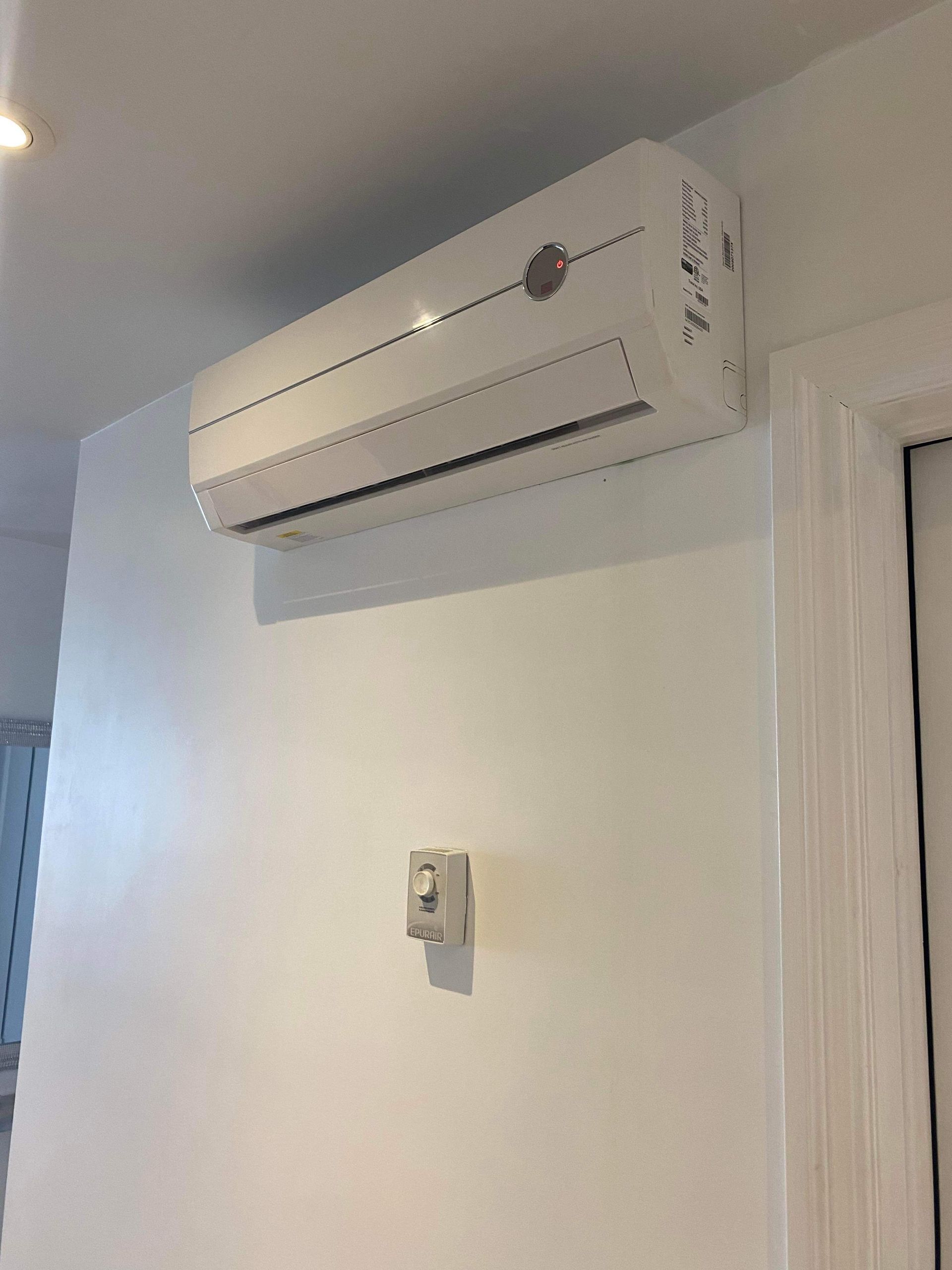 Un climatiseur blanc est monté sur un mur blanc.