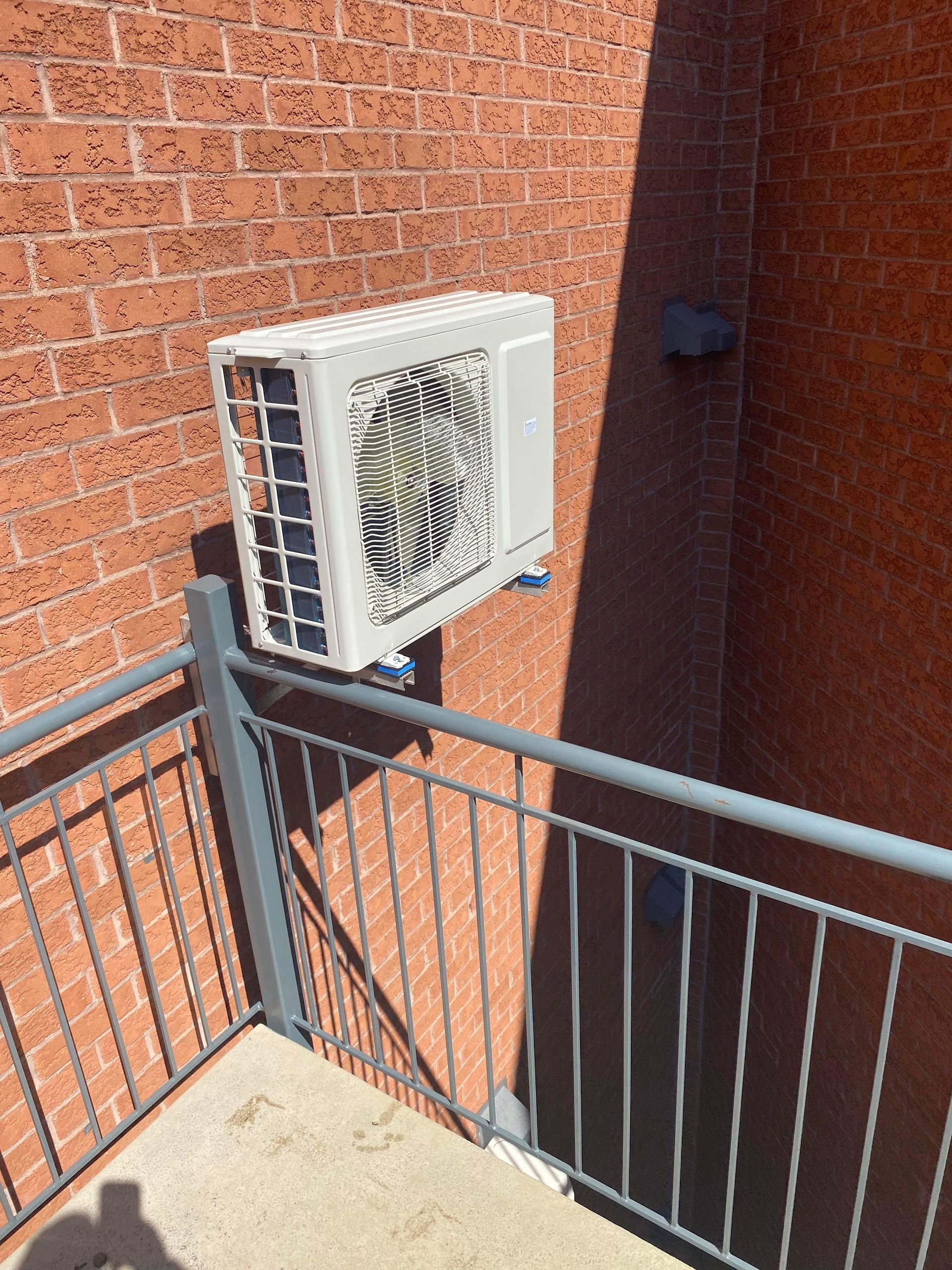 Un climatiseur est monté sur le côté d'un bâtiment en briques
