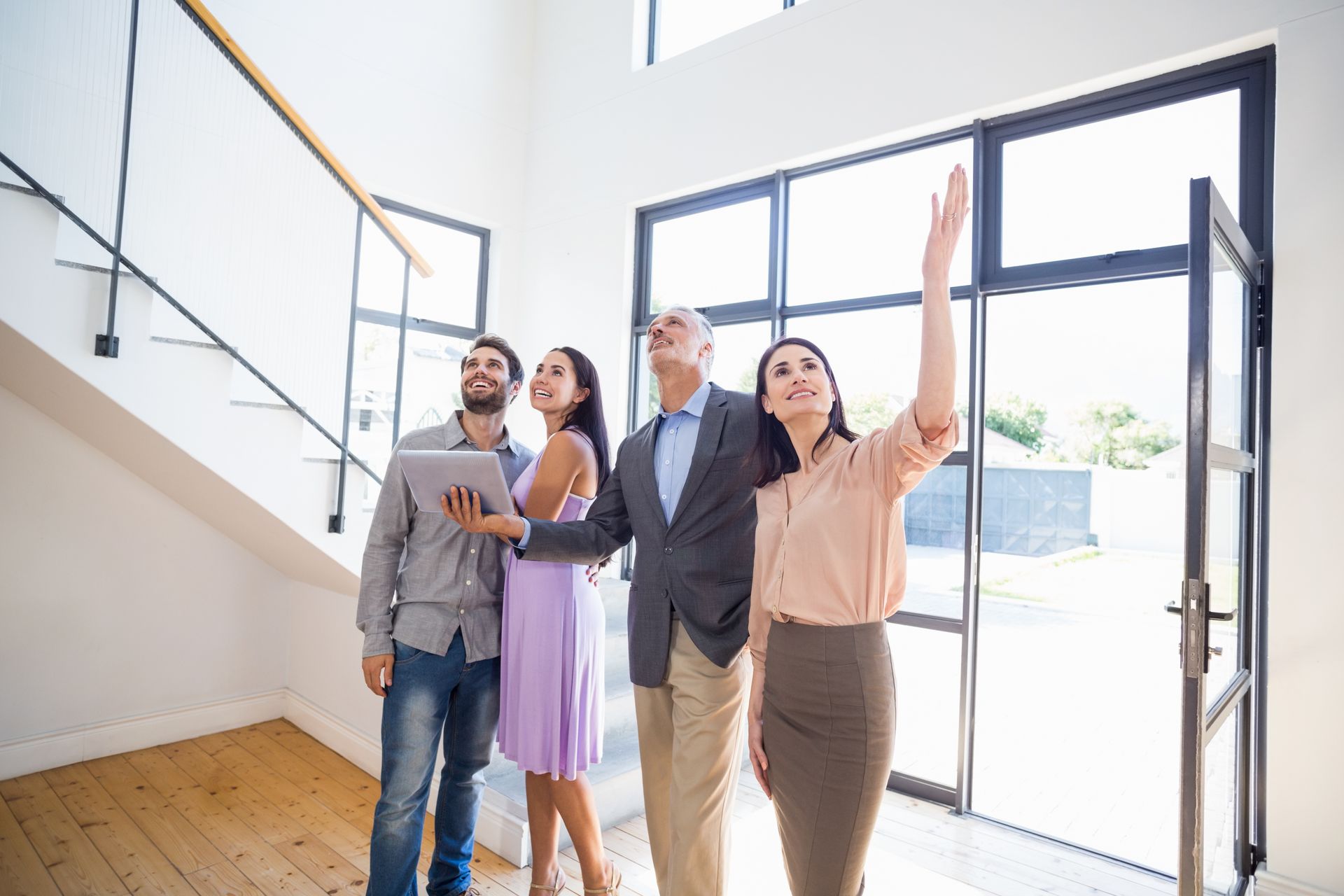 Group of four people in a bright modern home, one pointing at the ceiling and discussing the space.