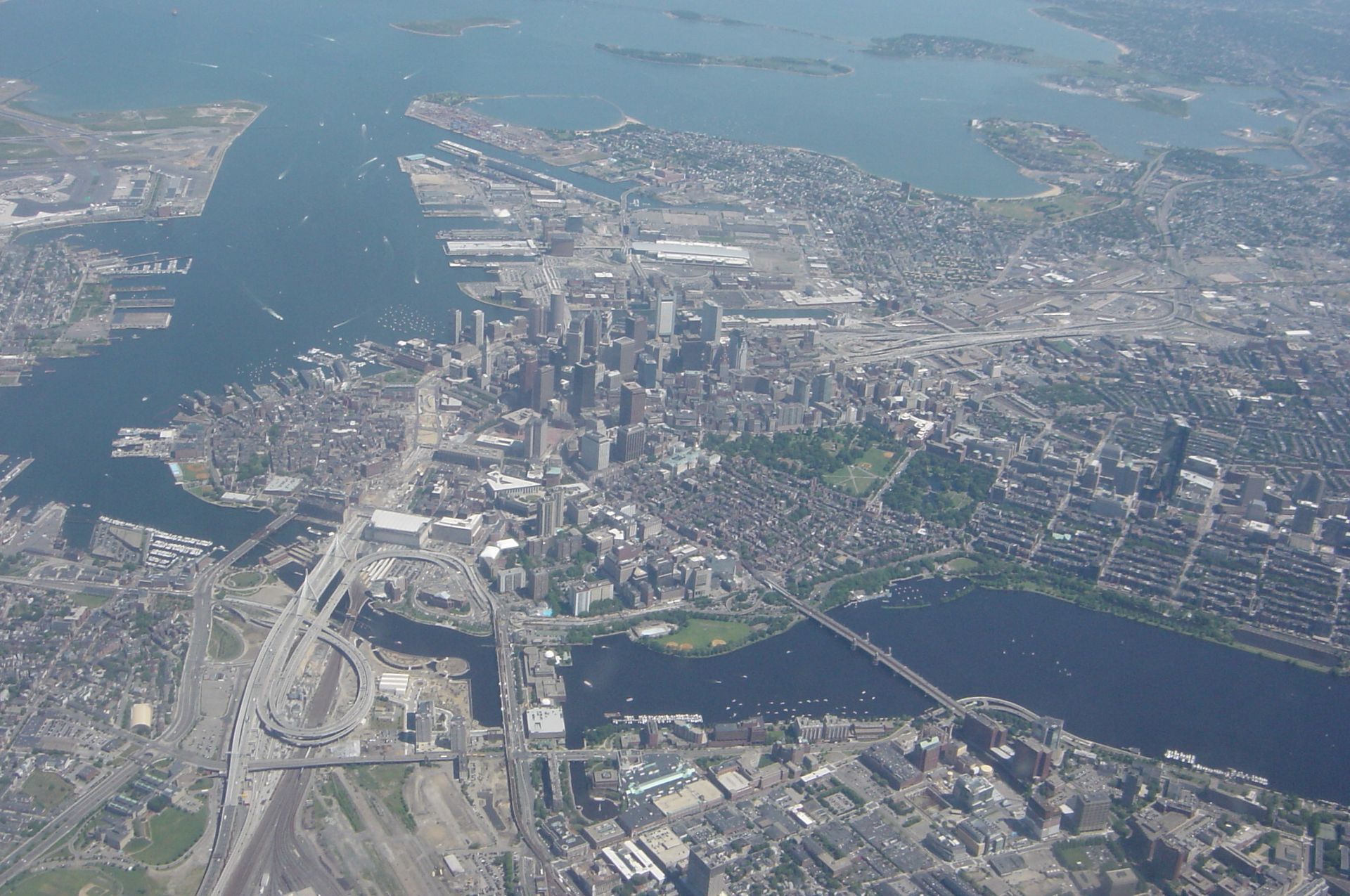 Aerial view of a coastal city with dense downtown buildings, highways, bridges, and blue waterways