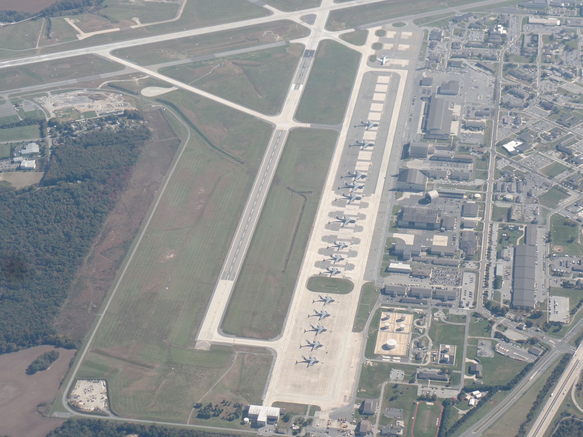 Aerial view of an airport runway and terminal buildings with planes parked along the apron.