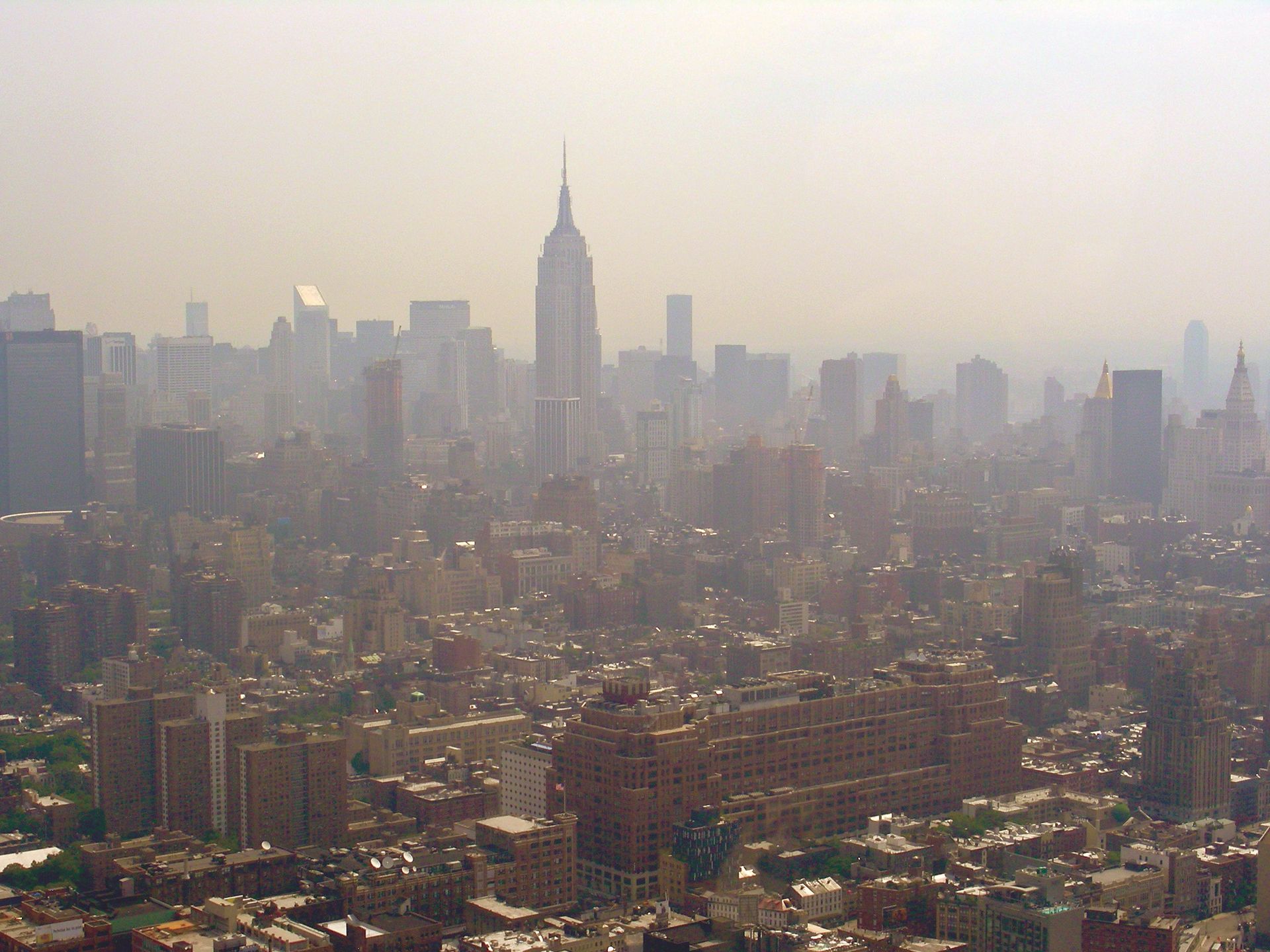 Hazy city skyline with the Empire State Building rising above dense low-rise buildings