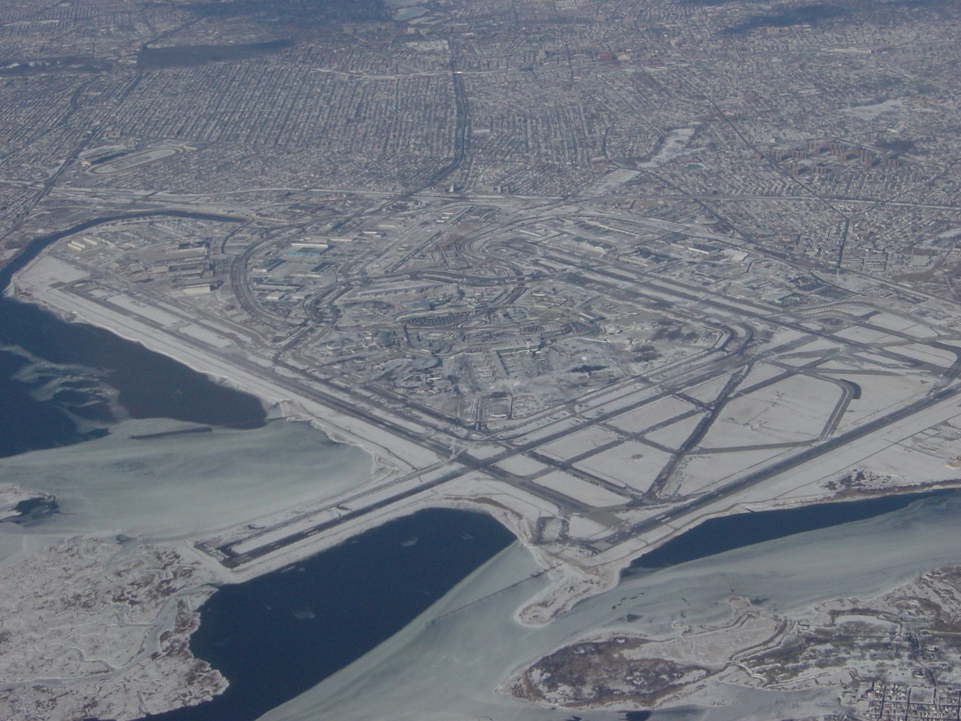 Aerial view of a snowy coastal city with roads, bridges, and a frozen harbor.