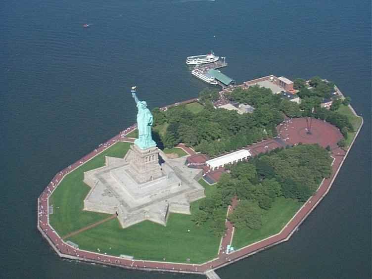 Aerial view of the Statue of Liberty on Liberty Island surrounded by water.