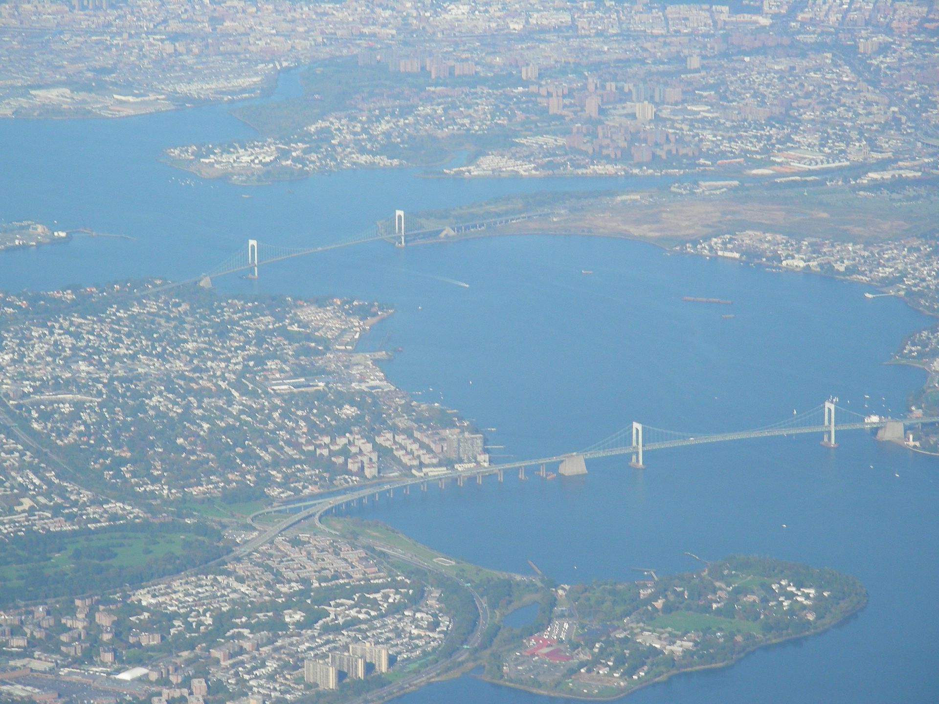 Aerial view of a city and bay with two large suspension bridges and surrounding shoreline.
