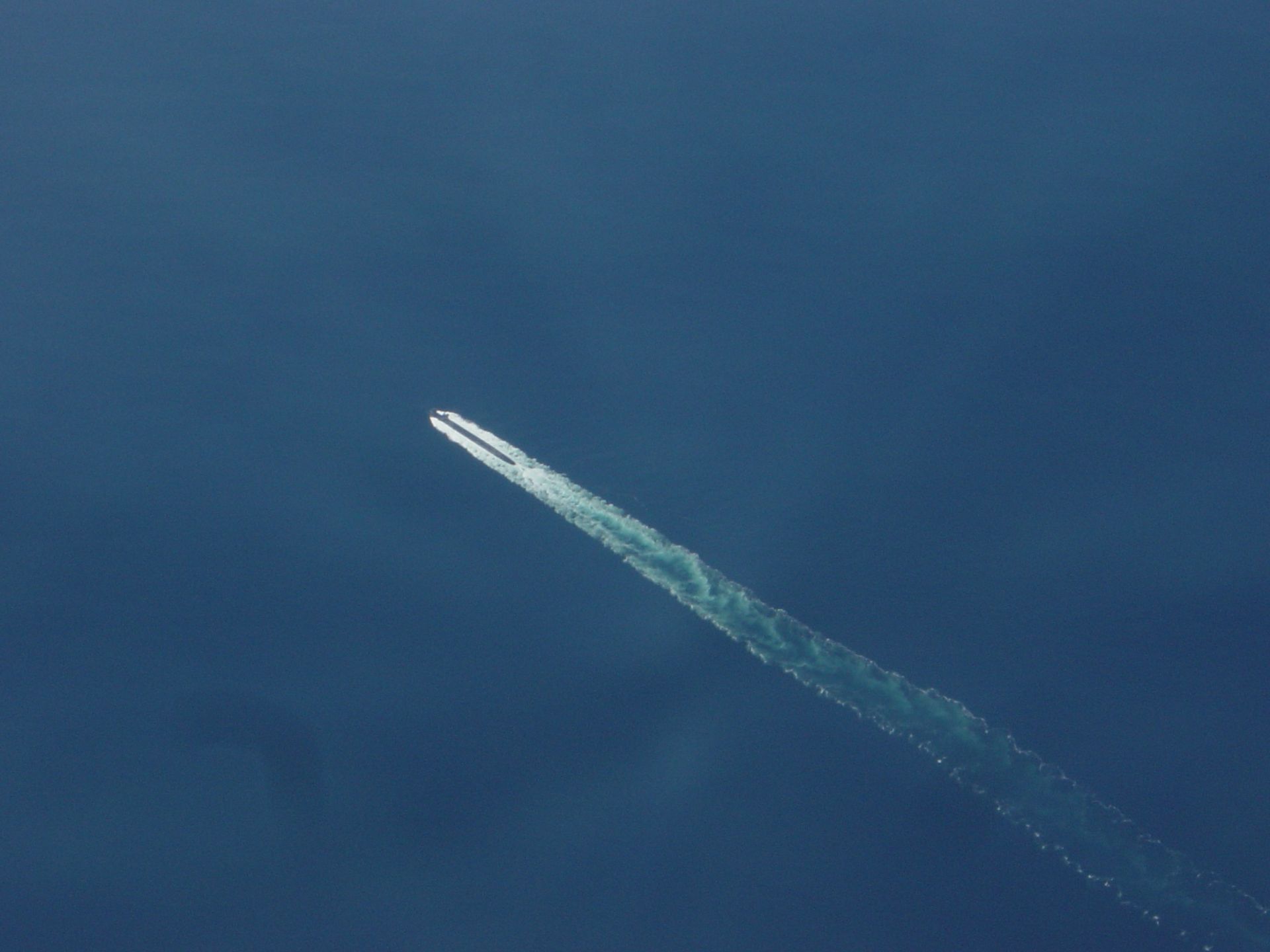 White jet trail arcs across a blue sky.
