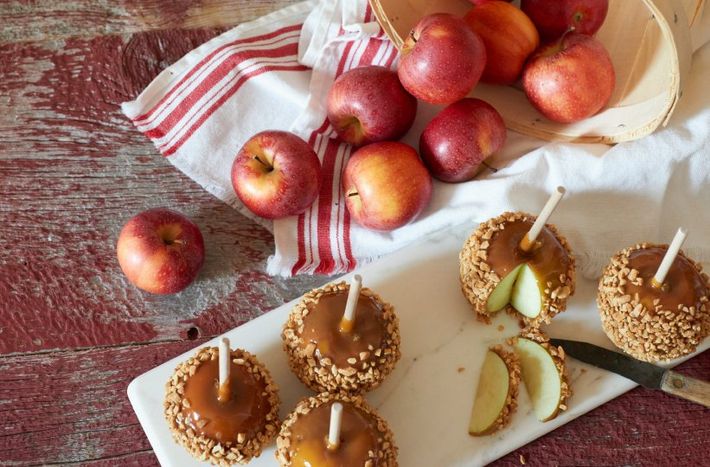 Caramel apples and fresh apples arranged on a rustic table with a red-striped cloth