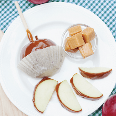 Assorted sweets on a white plate, including caramel candy, wrapped candy, and sliced fruit.