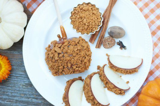 Pumpkin spice cookies and sliced apples on a white plate with cinnamon sticks and autumn decor