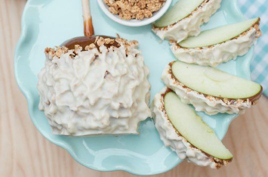 Caramel apple slices on a blue plate, one coated in white candy and coconut flakes.