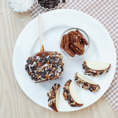 Dessert plate with chocolate-covered apple slices, pecans, and toppings on a white plate
