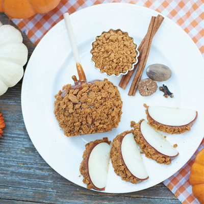 White plate with coconut treats, cinnamon sticks, and spices on a gray table with orange checkered cloth.
