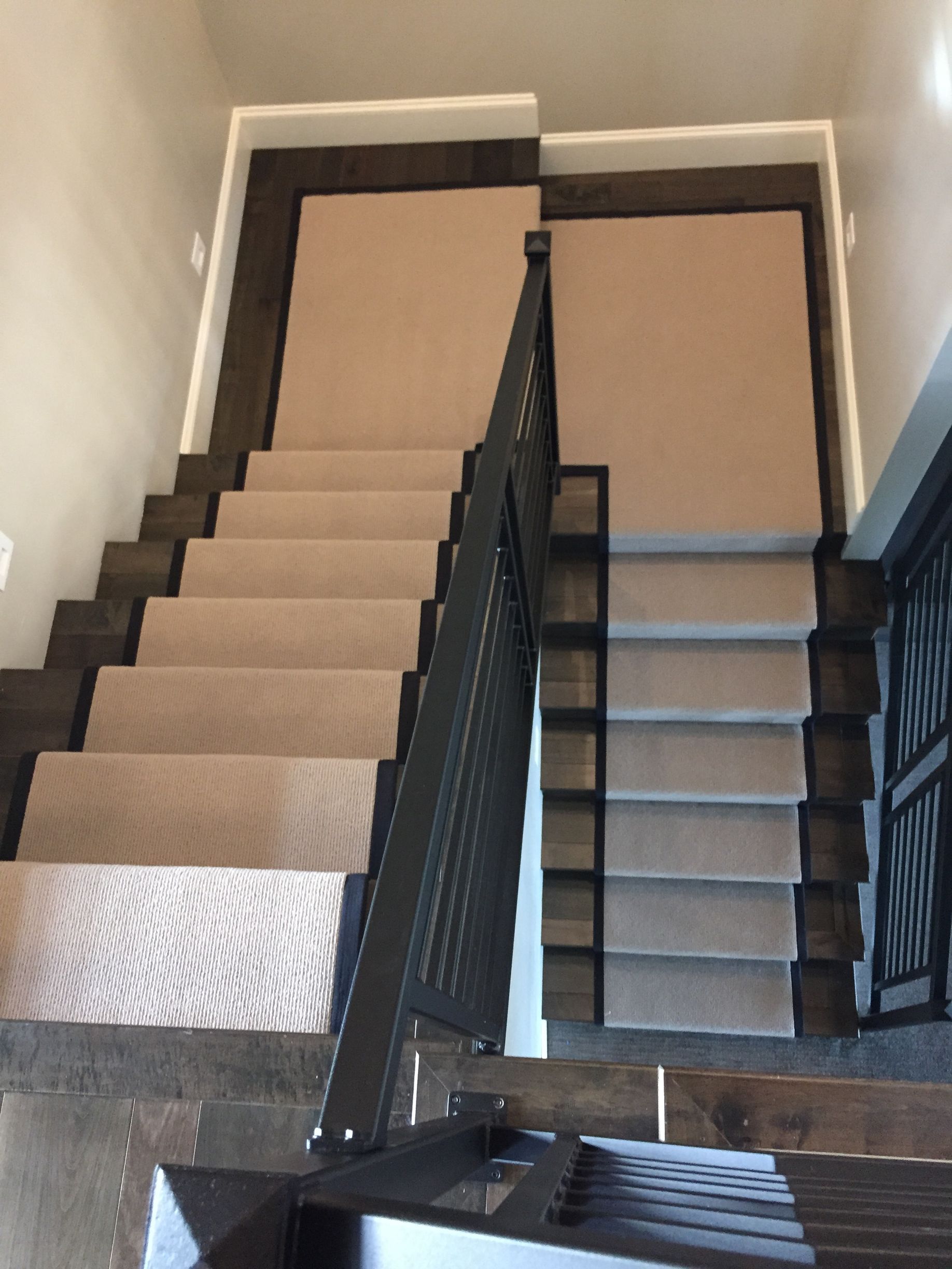 Split staircase with dual carpeted flights and black metal divider railing