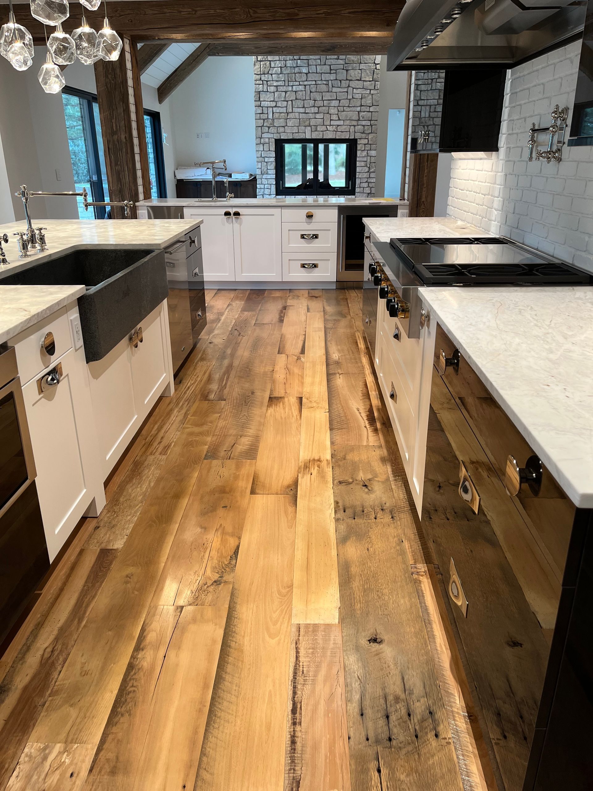 Kitchen with white cabinets, granite island, dark wood floors, and built-in stainless appliances