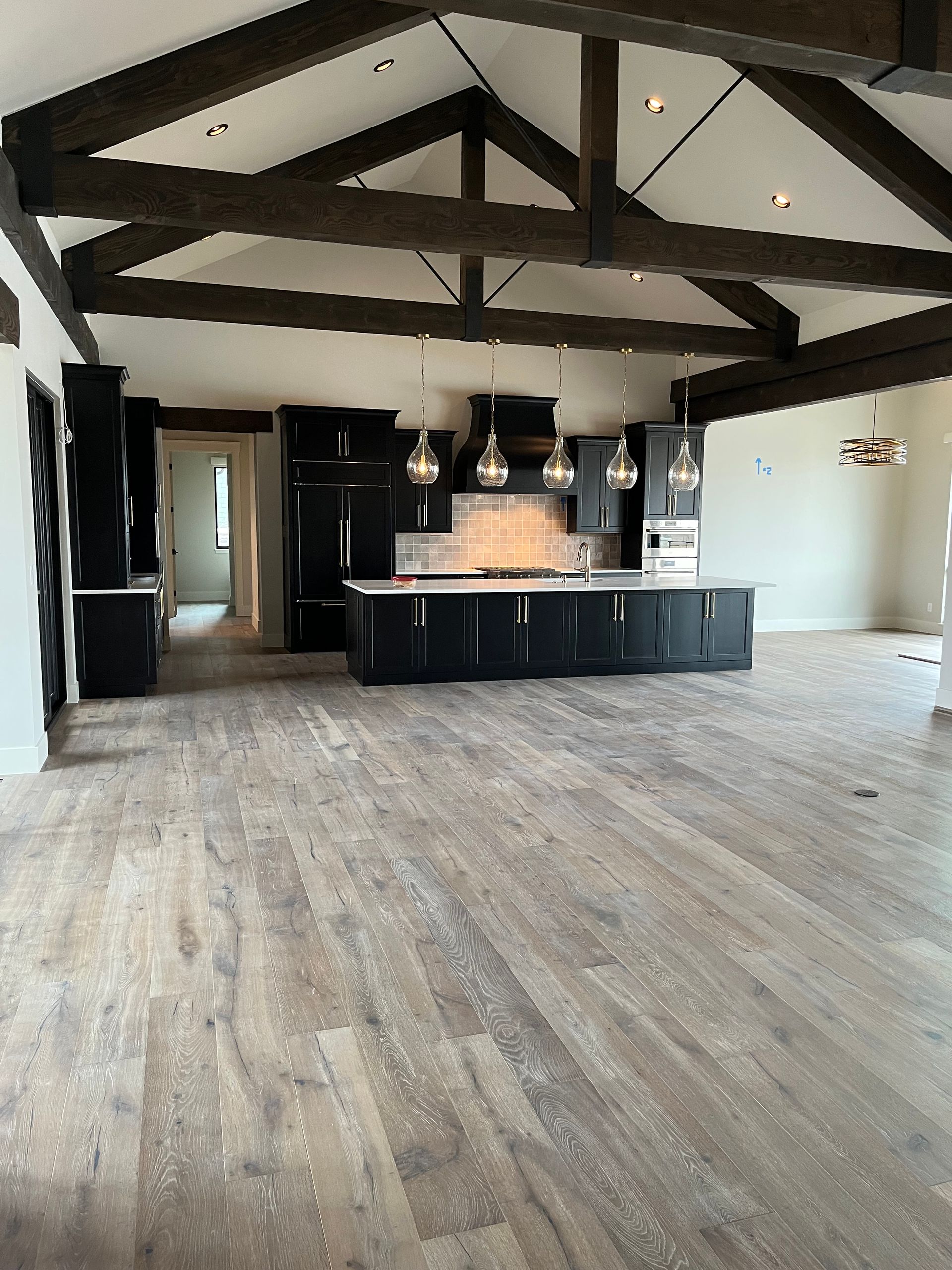 Vaulted kitchen with black cabinets, wood floors, and pendant lights