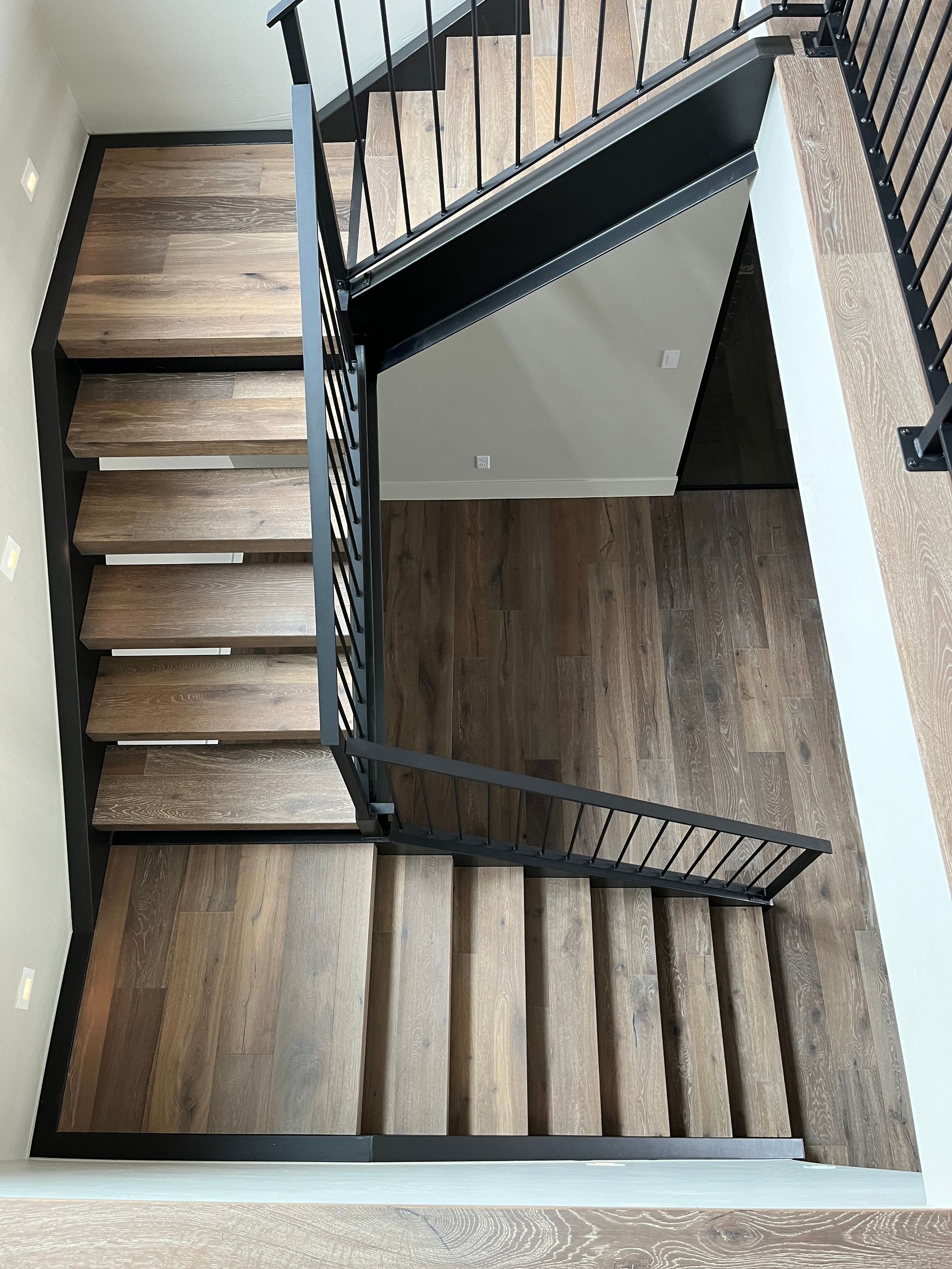 L-shaped staircase with wood steps and black vertical metal balusters
