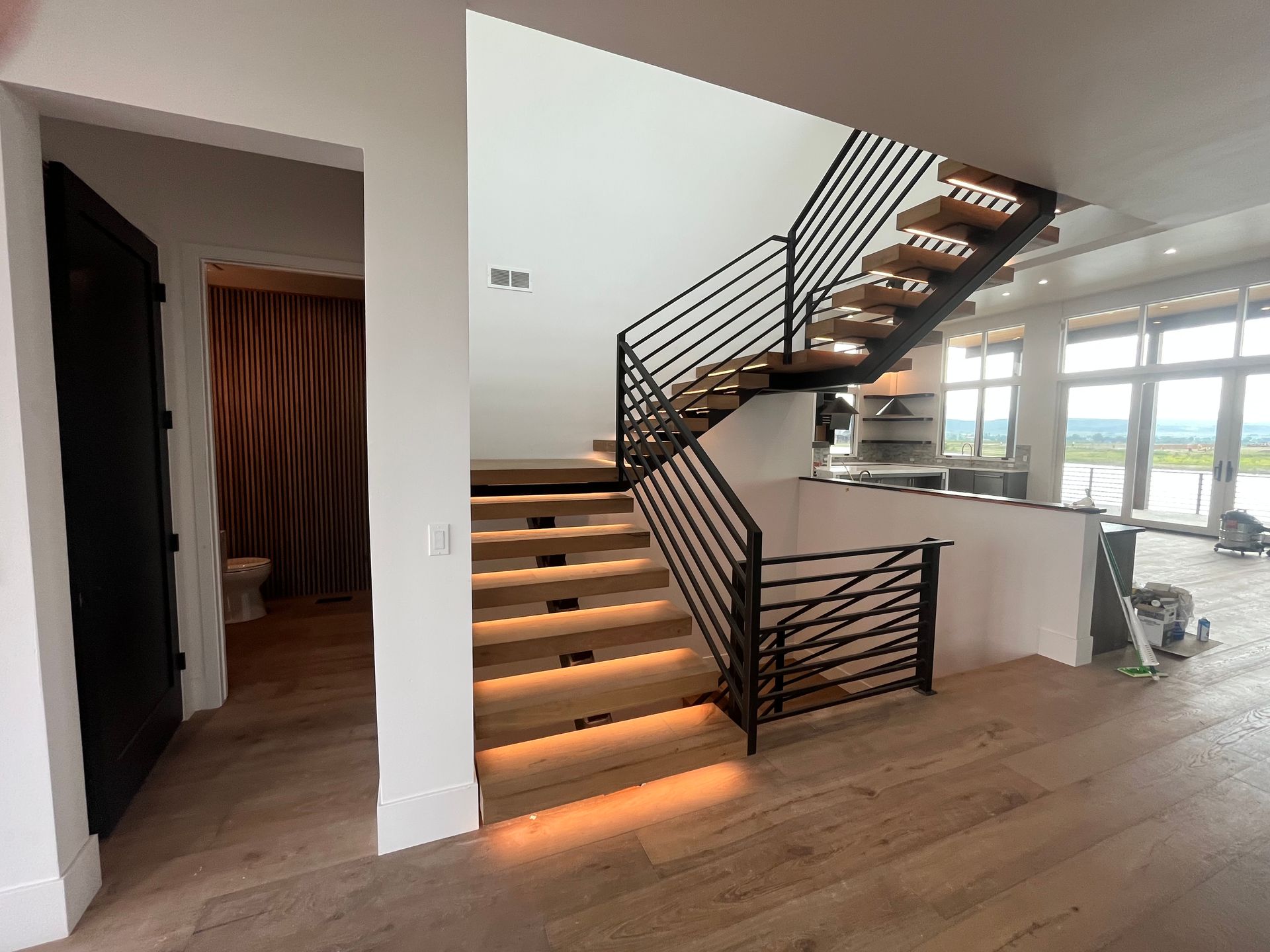 Modern staircase with under-step lighting and open-concept living area view