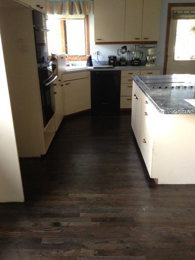 Kitchen with white cabinets, granite island, dark wood floors, and built-in stainless appliances