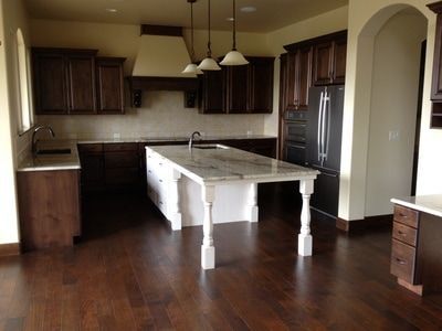 Kitchen with dark wood cabinets, marble island, stainless appliances, and arched doorway