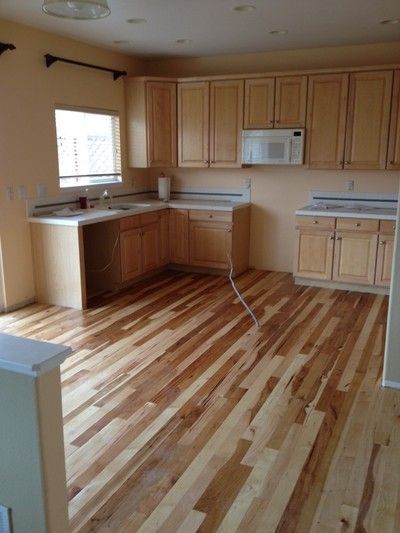 Kitchen with light wood cabinets, mixed-tone hardwood floors, and built-in microwave