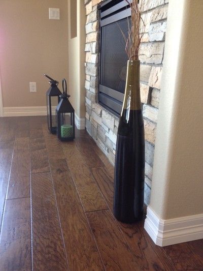 Decorative fireplace corner with lanterns, tall vase, and polished wood flooring