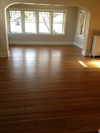 Empty room with arched alcove, five large windows, and polished hardwood flooring
