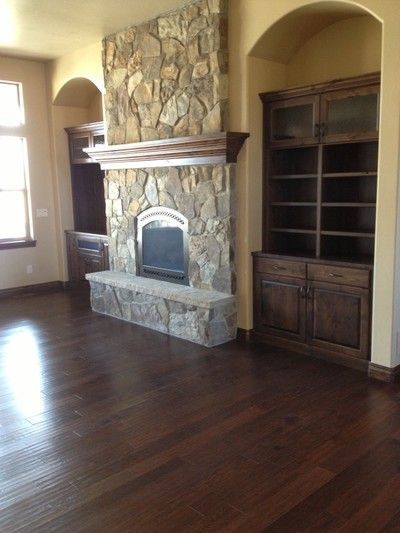 Living room with stone fireplace, built-in cabinets, arched niches, and dark hardwood flooring