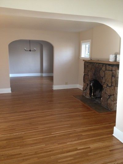 Unfurnished living room with stone fireplace and arched doorway to dining area