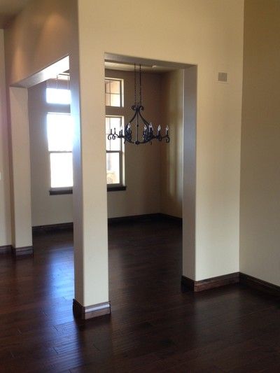 Elegant dining room with black chandelier, dark wood floors, and columned entryway