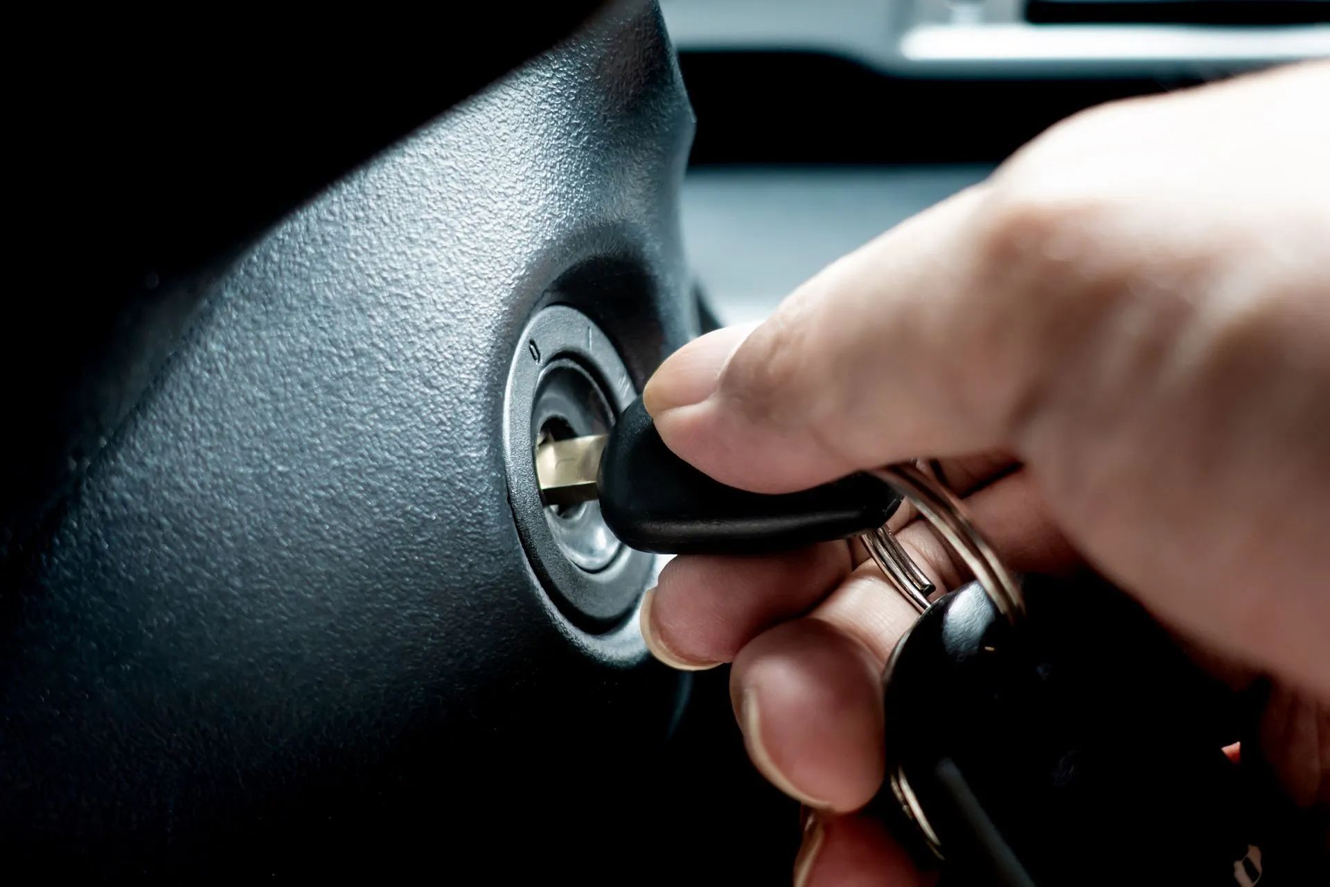 A person is holding a car key in their hand - Patterson Brothers Automotive